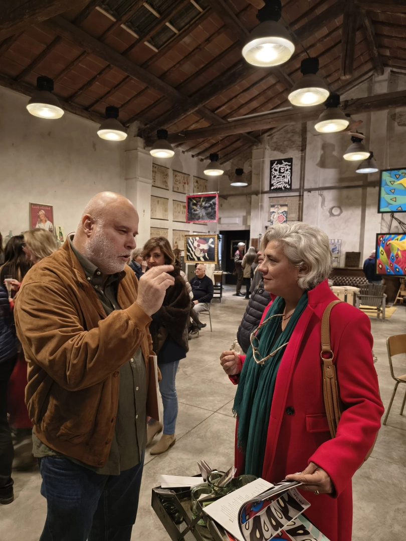 Oscar Salerni intento nello spiegare la sua visione artistica a una ospite dell'esposizione